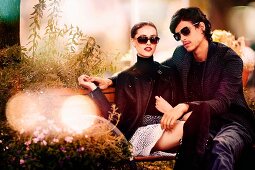 Verliebtes junges Paar sitzt auf Bank in Gartenanlage