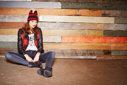 A young woman wearing jeans and a leather jacket sitting on the floor