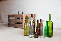 Various empty bottles in front of a wooden crate in a garage