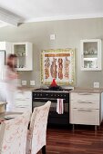 Painted and framed wall tiles as splashback behind gas cooker; place settings on counter in foreground