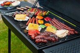 Sausages, skewers and vegetables on a charcoal barbecue