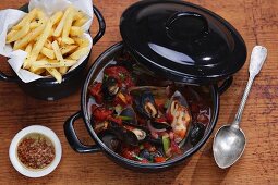 Mussel stew with chips on a wooden surface