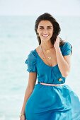 A young woman on a beach wearing a blue mini dress