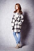 Junge Frau in Jeans und grauer Oversize-Wolljacke