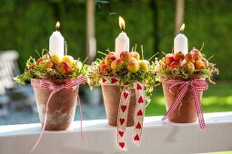 Candles and crab apples arranged in plant pots