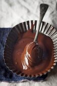Chocolate sauce in a metal bowl with a spoon