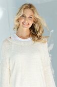 Junge blonde Frau in naturfarbenem Wollpullover