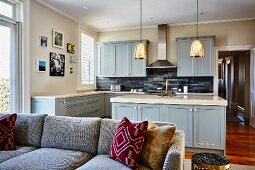 Blick über Sofa in offene Küche mit grau-blauen Fronten im Landhausstil
