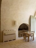 Arched niche and masonry sideboard next to small dining table and chairs in restored Apulian trullo