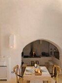 Set dining table in front of arched niche with open fireplace in rustic Apulian trullo