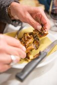 Hands cutting carciofi alla giudia (fried artichokes, Italy)