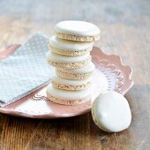 A stack of macaroons on a plate with one leaning against a plate