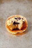 A yoghurt cupcake with blueberries and crumbles with a bite taken out