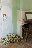 Floral cover on terracotta floor next to open antique fireplace in rustic Mediterranean interior