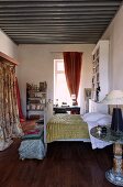 Quilt on antique sleigh bed and wardrobe with patterned curtain in Mediterranean interior