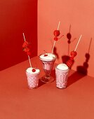 A strawberry milkshake with cream and cocktail cherries