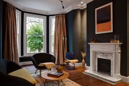 Black-painted room with bay window, retro seating and open fireplace