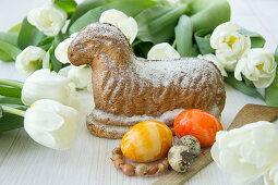 Painted Easter eggs, white tulips and Easter lamb cake