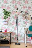 Retro standard lamp in front of wallpaper with floral cross-stitch pattern