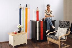 Brightly coloured painted stripes on wall and continuing over chest of drawers