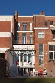 Mehrstöckiges traditionelles Stadthaus aus Ziegel; Hochparterre mit Balkon-Treppe und Terrassenplatz