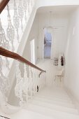 White balustrade in stairwell leading down into white hallway of period apartment