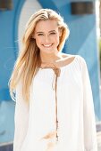 A young blonde woman wearing a white blouse with a leather cord