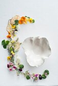 Various fresh herbs with edible flowers and fried pear chips around a soup bowl