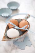 Hen's eggs with a ribbon in a small wooden scoop on a marble surface