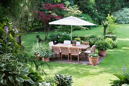 Seating area below parasol in neat garden