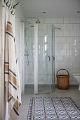 Glass shower cubicle in bathroom with white-tiled walls