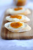 Slices of white bread, topped with butter and apricot spread