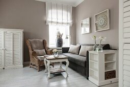 Wicker wing-back chair, couch and coffee table below window in corner of elegant living room