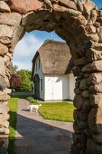 Blick durch Torbogen aus Naturstein auf Ferienhaus