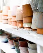 Various stacked terracotta pots on white shelf