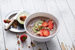 A bowl of avocado smoothie with strawberries and kiwi