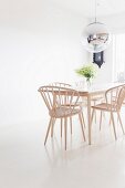Helle Holzstühle um Tisch in skandinavischem Stil auf weißem Boden, oberhalb Kugelleuchte mit Spiegelung