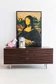 Modified painting of Mona Lisa, bird-shaped table lamp and vases below glass cover on top of sideboard