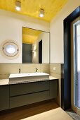 Minimalist designer bathroom with porthole window and wooden ceiling