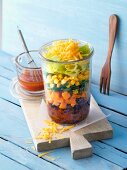 A layered sweet potato salad with beans in a glass