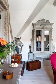 Antique grey display cabinet and bust with donkey head in corner of converted attic
