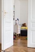Offene weiße Flügeltür in Altbauwohnung mit durchgehendem Fischgrätparkett, Blick ins Kinderzimmer