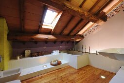 Modernes Bad mit Lärchenboden und weissen Einbauten; Dachschräge mit sichtbarer, rustikaler Holzkonstruktion und Dachflächenfenster