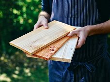 A man holding various wooden boards for grilling