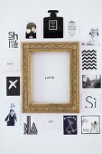 Postkarten und Fotos mit verschiedenen Motiven um goldenen Bilderrahmen mit 'Love'-Botschaft an Wand