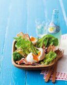 A salad with a soft-boiled egg, bacon and green asparagus