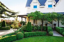 Topiary hedges in front of an elegant country house with an all-round canopy