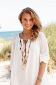 Junge blonde Frau in weisser Tunika am Strand
