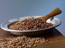 Brown lentils on a metal plate on a wooden table