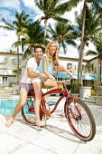 A young couple sitting on a bike together